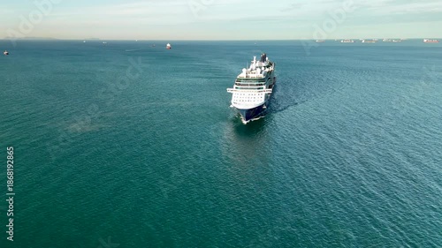Aerial drone view of a large cruise ship sailing across calm blue ocean waters under clear sky vessel moves steadily through the sea symbolizing luxury travel  tourism maritime transportation and ocea