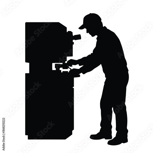 Silhouette of a man operating industrial machinery in a factory setting