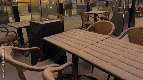 Wallpaper Mural Quiet winter scene outside bistro, Serene snowy outdoor cafe with muted city lights and wicker furniture Torontodigital.ca