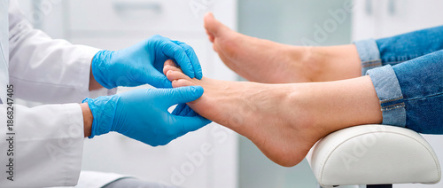 Podiatrist in blue gloves examining patient's foot in a medical clinic