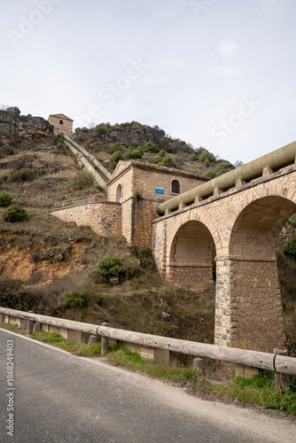 Historic structures on a hillside near a road.. Pueblo de Patones de Arriba in Madrid, famous for its slate architecture and for evading the French invasion.