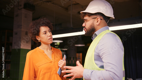 Φωτογραφία Male project manager discussing building plan with female engineer in hard hat a