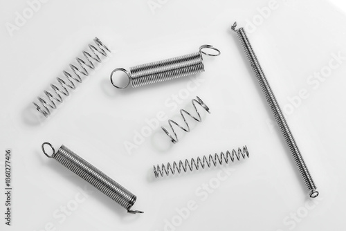 Six metal springs of various shapes and sizes arranged on a white background, ideal for mechanical or industrial themes.