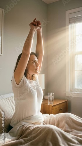 Wallpaper Mural Young woman stretching in bed waking up in the morning with bright sunlight. Vertical shot of a female starting her day with energy near a window with sunbeams. Healthy lifestyle concept Torontodigital.ca