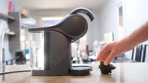 Close-up of a capsule coffee maker with a glass cup and coffee pod, representing quick and convenient coffee preparation.