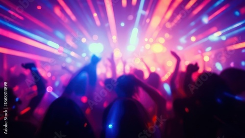 Blurred crowd dancing at night club with dynamic light effects