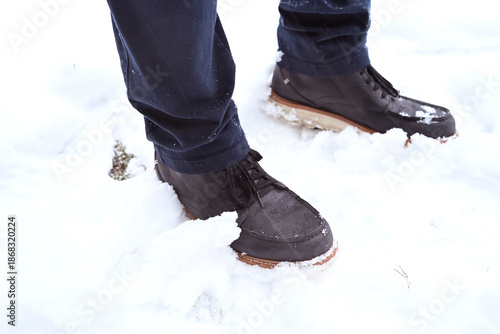 Person standing and walking outdoors in winter snow wearing boots. Concept of winter lifestyle, cold weather, everyday activity, seasonal weather, and outdoor walking in natural conditions.