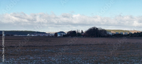 Paisaje rural de campos cultivados con escarcha bajo un cielo azul con nubes blancas en la lejanía en Burgos, España