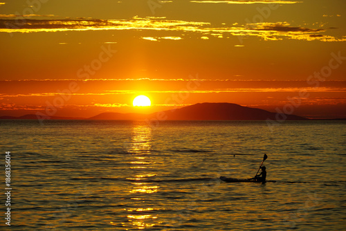 Summer adventure of young boy who enjoying paddleboarding at sunset