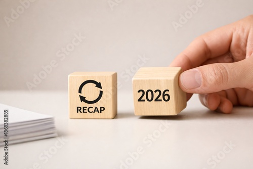 Hand moving the 2026 block for yearly recap and analysis of 2025 economy, useful for corporate agreement presentations