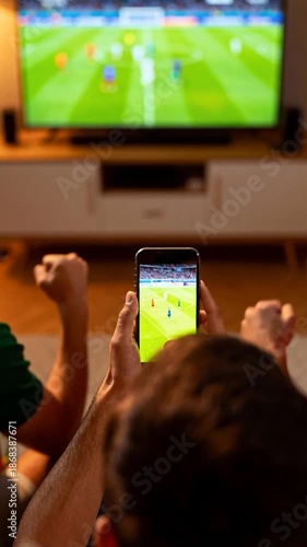 Soccer fans watching match on smartphone and television simultaneously while celebrating at home