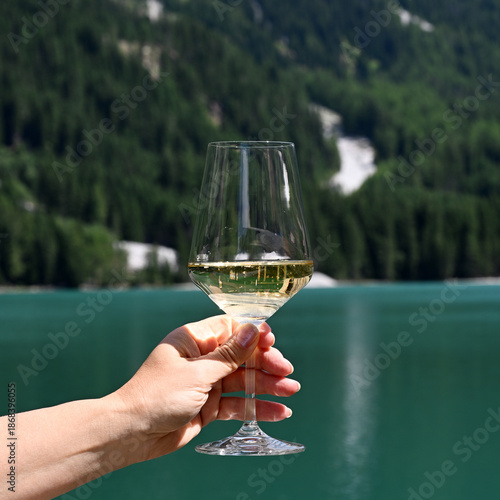 Female hand with glass of sparkling wine against lake