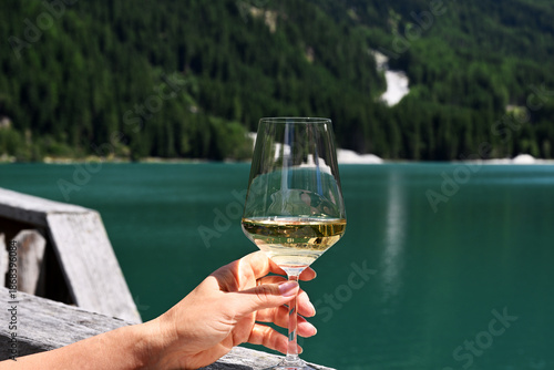 Female hand with glass of sparkling wine against lake