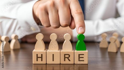 Manager's hand carefully selects the perfect candidate represented by a distinctive green person figurine above the word hire