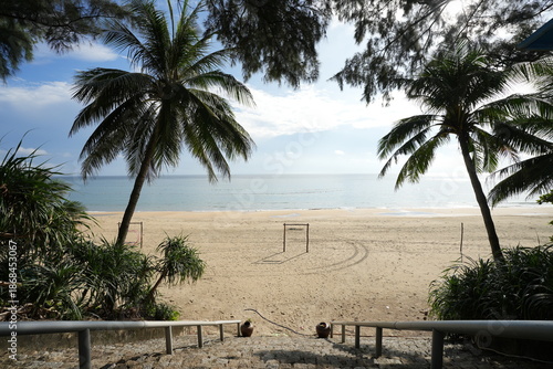 Stone steps lead down to a sunny Lang Co beach framed by palms, with golden sand and calm blue ocean waters.