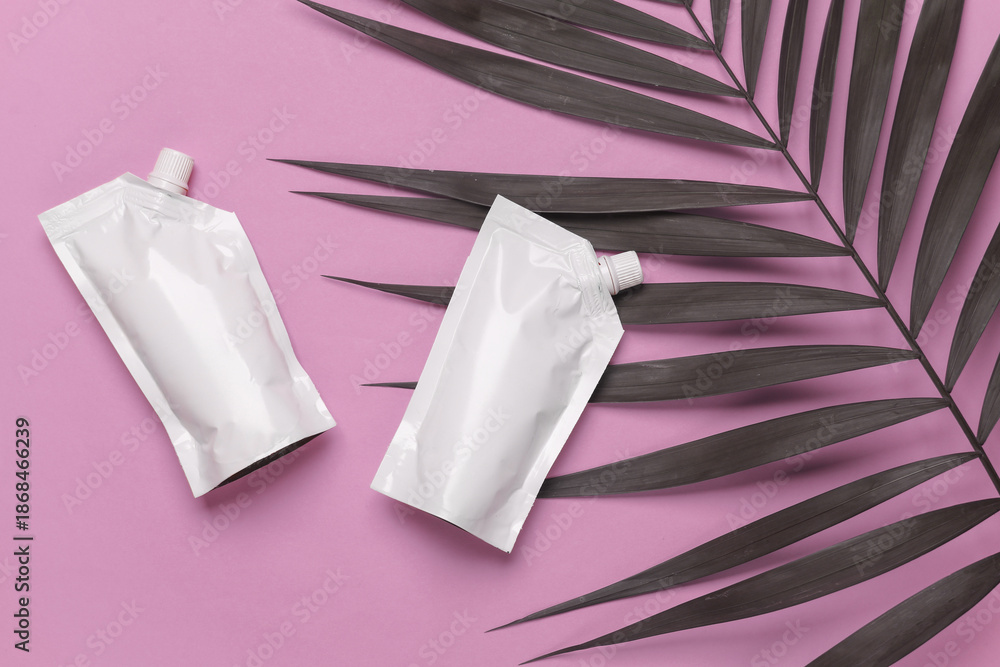 Naklejka premium White Doypacks on pink background with palm leaf