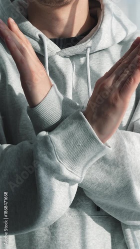 A man in gray clothes protests and crosses his arms.
A sign of rejection and non-acceptance.
A STOP gesture.
A man says no with gestures.
Crossed arms, negativity, and rejection.