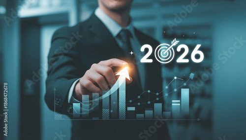 Anonymous business professional in a dark corporate environment, pointing toward a glowing holographic arrow moving upward into the future. Floating year text “2026”.