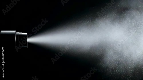 Powerful spray nozzle releasing dense white mist cloud against dark background in studio lighting
