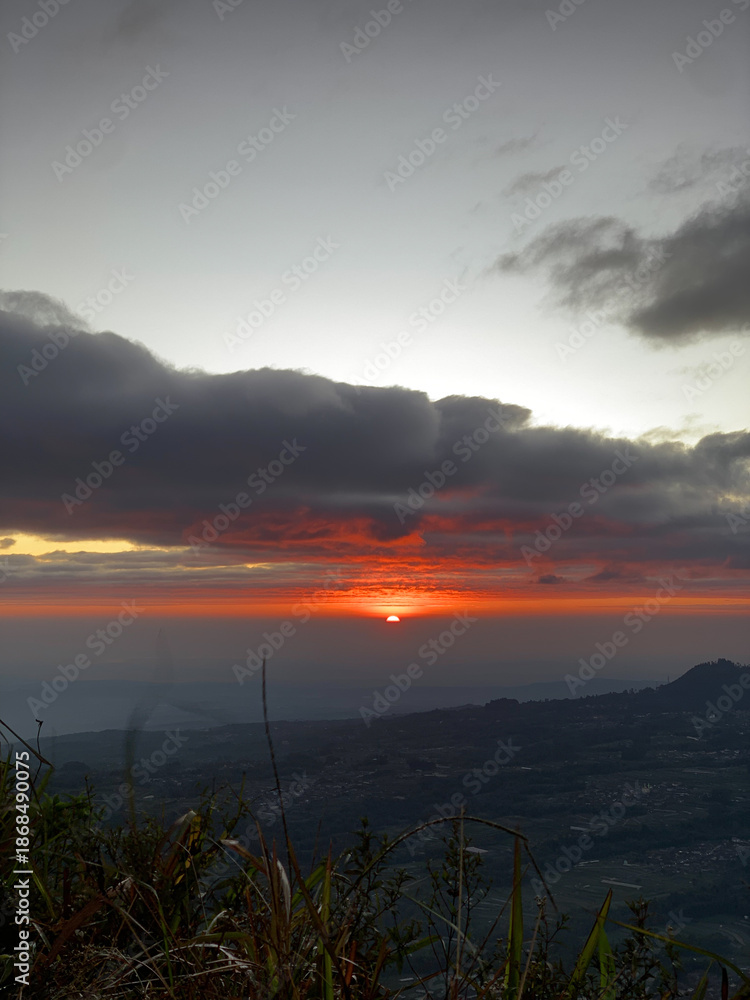 Obraz premium Sunrise over misty mountain landscape with dramatic clouds
