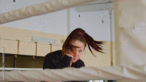 Shadow fighting workout - 4k footage. Female boxer is practicing shadow boxing. Close-up view between the ropes of the ring.