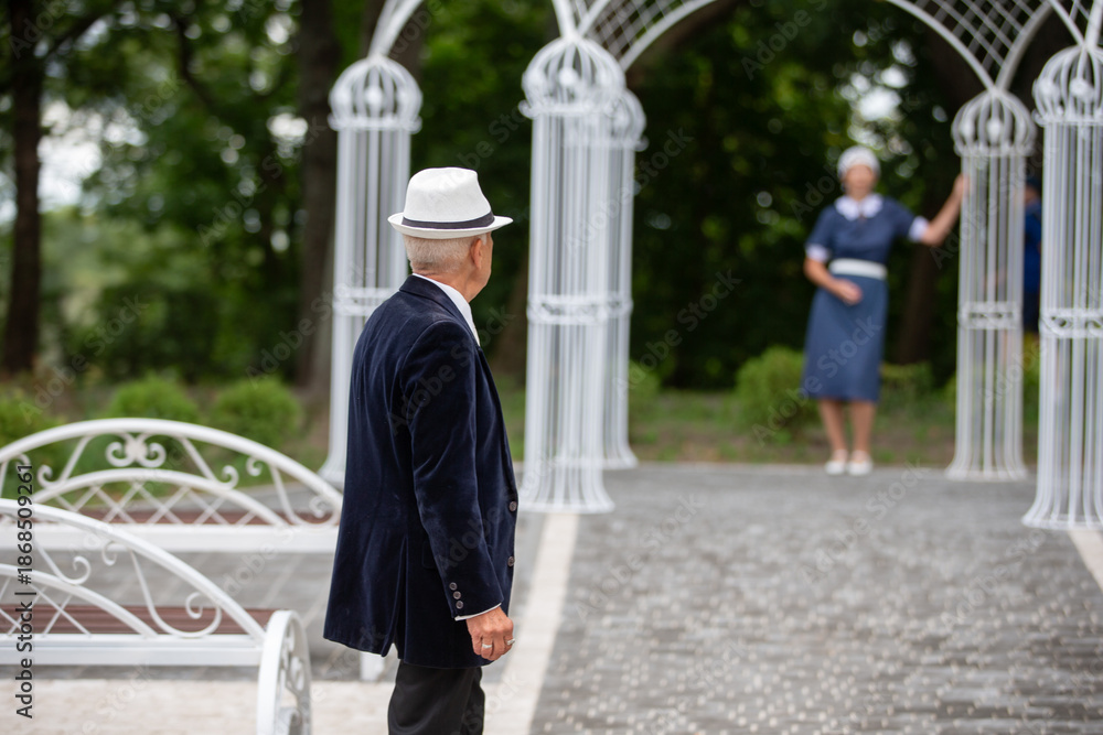 Obraz premium Couple reuniting at a garden arch during a sunny day in a tranquil park setting in summer