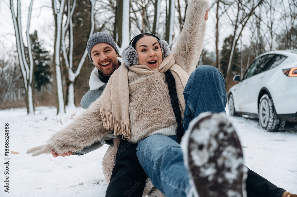Obraz premium Happy couple enjoying winter fun in snowy landscape, laughing and playing together, showcasing joy and connection in a beautiful outdoor setting