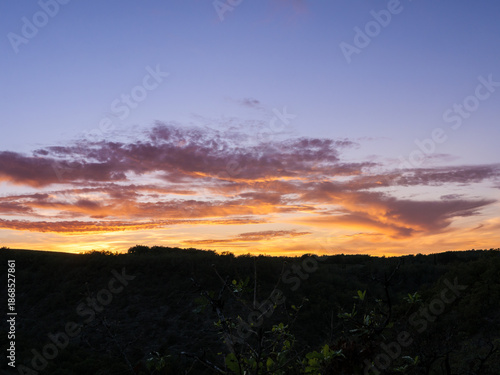 Sunset Over Forested Hills with Orange and Purple Clouds