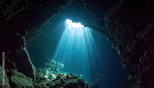 Sunlight streams into a dark underwater cave, creating ethereal beauty.