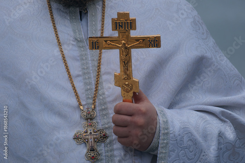 Tableau sur toile Close-up of an Orthodox priest's hand holding a golden liturgical cross during a winter religious ceremony