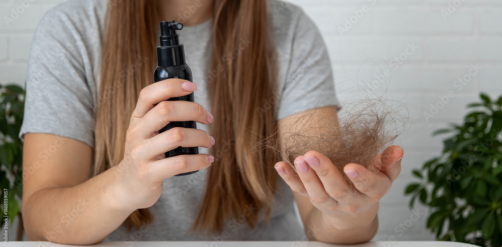 Naklejka premium Woman holding fallen hair and a medical spray bottle. Hair loss treatment concept