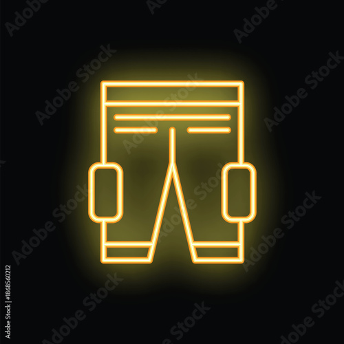 Yellow neon sign depicting ice hockey player pants with knee pads glowing on a brick wall