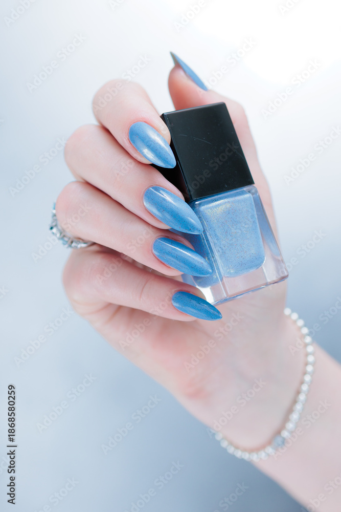 Fototapeta premium Woman's beautiful hand with long nails and light baby blue manicure 
