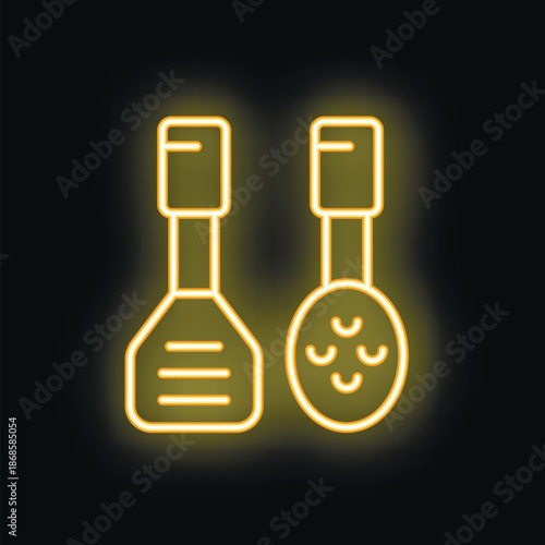 Neon yellow kitchen utensils spatula and skimmer glowing on black background