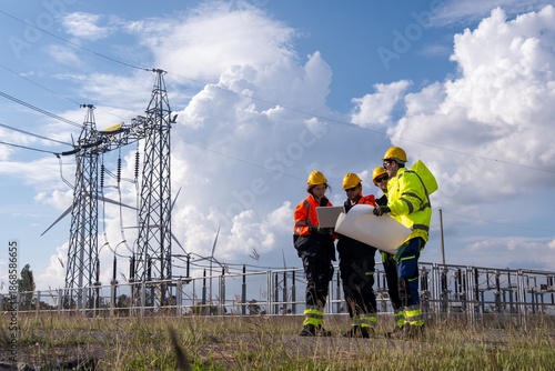 Team of workers discussing plans near power lines under cloudy sky in the daytime