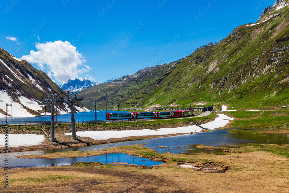 Φωτογραφία View of a local train traveling along the Lake Oberalp with snowy alpine mountai