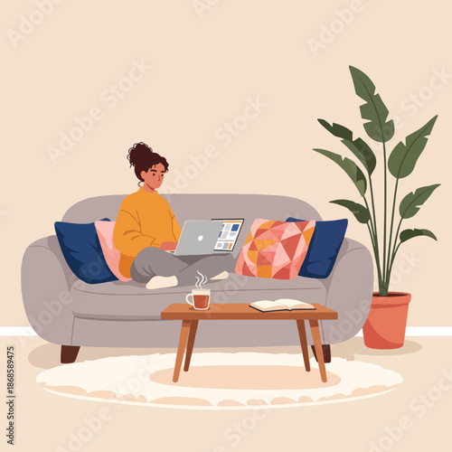Woman sitting on gray couch with laptop.