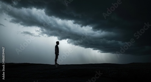 Silhouette of a person under a dark, stormy sky with ominous clouds