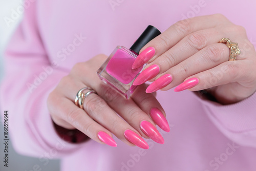 Female hand with long nails and a bright neon pink color nail polish