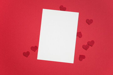 Blank greeting card mockup on vibrant red background with scattered red heart shapes, perfect for Valentine's Day design projects and romantic messages