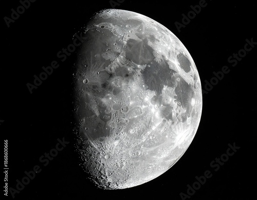 Illuminated celestial body's side reveals craters and rough textures against a deep black background