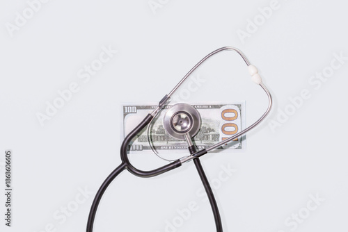 Stethoscope Lying on One Hundred Dollar Bill over Plain Light Blue Background. Conceptual Visual for Healthcare Costs, Medical Insurance Expenses, Paid Medicine and Economic Aspects of Health Services
