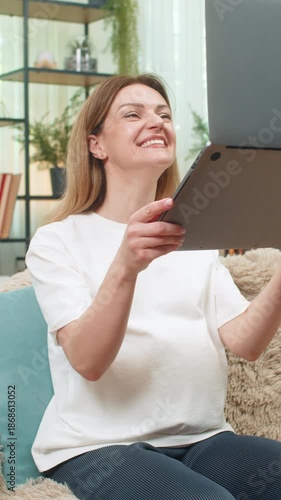 Pregnant middle-aged woman at home sees job approved on laptop lifts laptop laughs touches belly big joy. Caucasian girl on sofa celebrates new income milestone feels so proud hopeful for baby future.