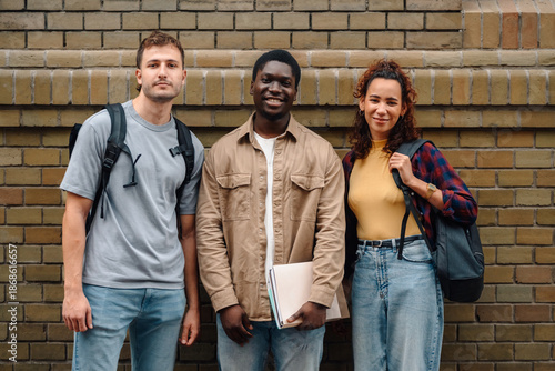 University students standing together against brick wall