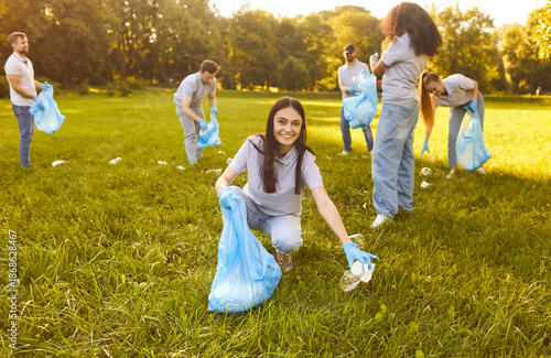 Fotografia Diverse group of people, friends volunteering in sunny, grassy green park, picki