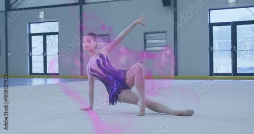 Posing teenage dancer holding floor pose inside ice rink facility, purple leotard and magenta haze