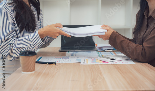 Handing Over: A collaborative office scene as one individual hands over documents to another, fostering seamless teamwork and efficient communication. 