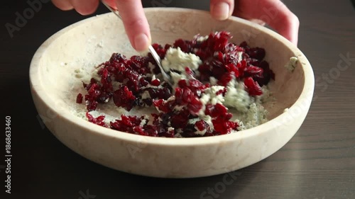 blue cheese and dried cranberries being mixed into a smooth mixture