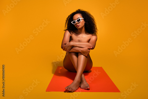Fotografia Gorgeous young woman with fashionable sunglasses posing against a vibrant orange