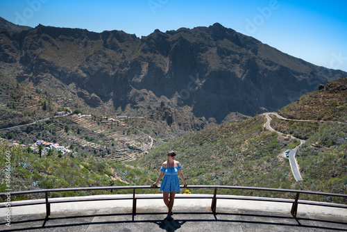 A girl in a blue dress poses against the backdrop of the Canary Mountains.